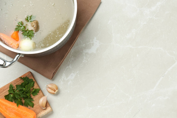 Pot with delicious bone broth and ingredients on light grey table, flat lay. Space for text - Foto, immagini