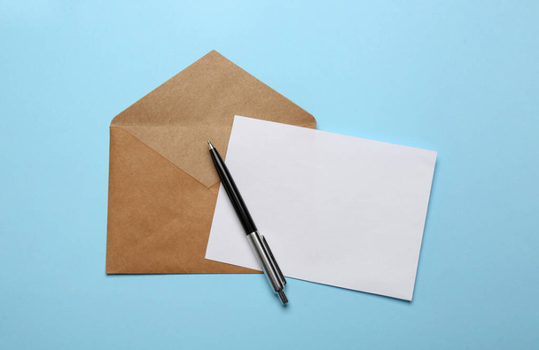 Brown envelope with blank letter and pen on light blue background, top view - Fotografie, Obrázek