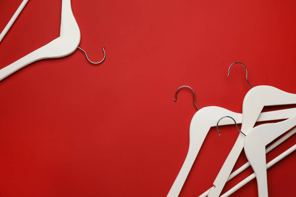 Empty clothes hangers on red background, flat lay. Space for text - Фото, изображение