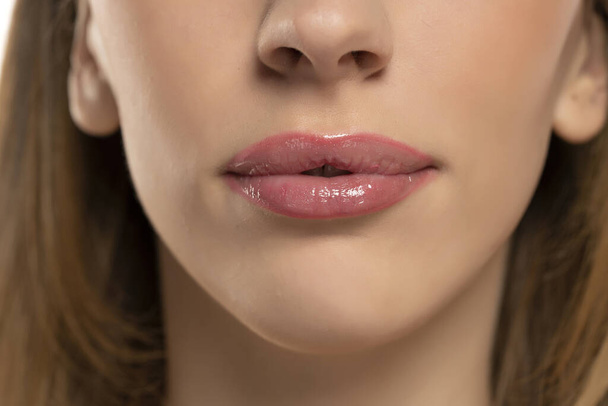 Όμορφα πρησμένα θηλυκά χείλη με γυμνό κραγιόν σε λευκό φόντο - Φωτογραφία, εικόνα