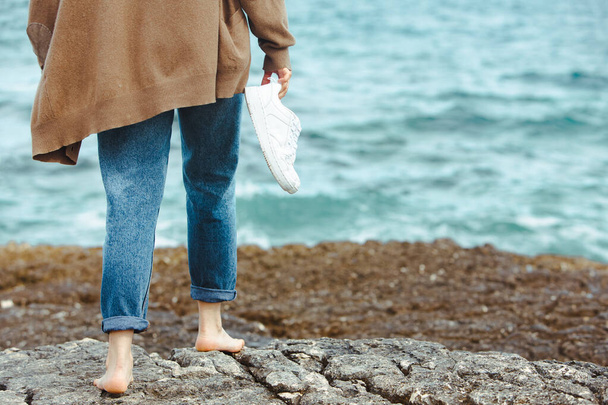 donna che cammina a piedi nudi dal mare tenendosi per mano scarpe bianche. vacanze estive. unione della natura
 - Foto, immagini