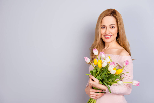 Retrato de persona encantadora alegre celebrar flores frescas mirar cámara aislada sobre fondo de color gris - Foto, imagen
