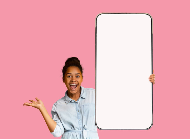 Emocionado adolescente negro chica mostrando smartphone con pantalla vacía - Foto, Imagen