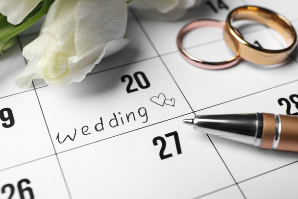 Calendar with date reminder about Wedding Day, pen and rings, closeup - Foto, Imagen
