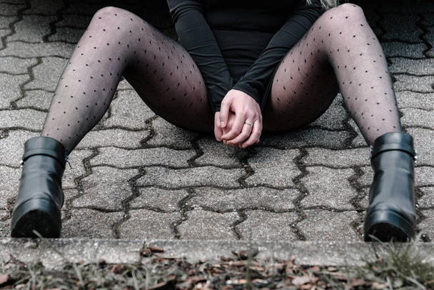 Naylon çorap ve siyah ayakkabılarla oturan bir kadın kışkırtıcı bir poz verir. - Fotoğraf, Görsel