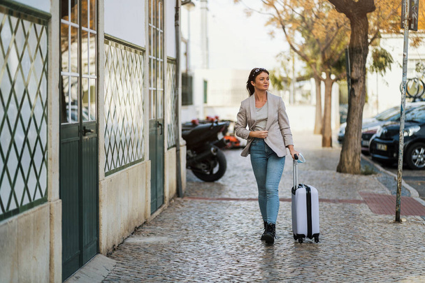 Portrait of traveling woman with luggage in urban settings - Zdjęcie, obraz