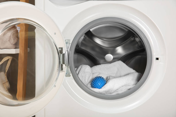 Blue dryer ball and towel in washing machine drum - 写真・画像
