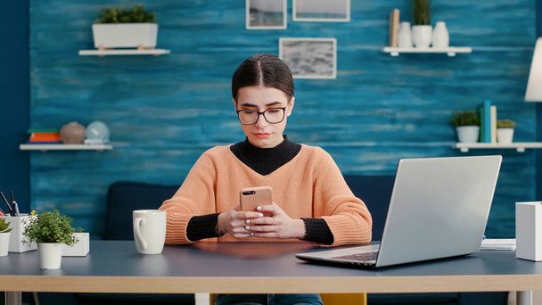 Person sitting at desk and using smartphone to browse internet - Photo, Image
