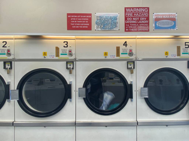 Laundrette Row of industrial laundry machines in laundromat in a public laundromat, with laundry uk  - 写真・画像