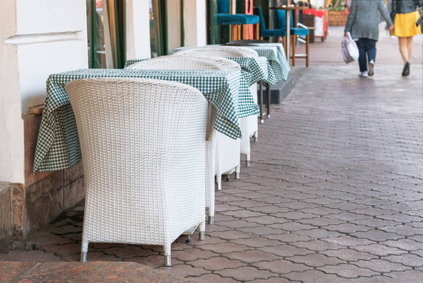 Yazın boş oturma alanı. Caddedeki yazlık kafe terasında beyaz masalar ve koltuklar. Restoran işi ziyaretçileri bekliyor.. - Fotoğraf, Görsel