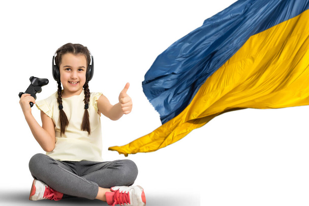 fille regardant les leçons à la maison ordinateur portable. enseignement à distance sur le fond du drapeau ukrainien - Photo, image