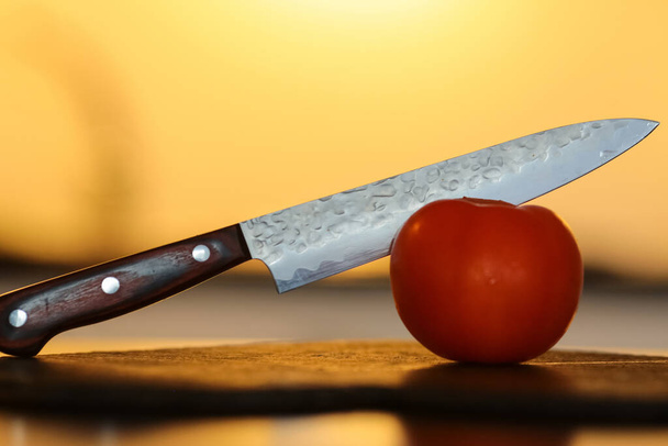 Ножі для різання помідорів на дерев'яній дошці з жовтим тлом
 - Фото, зображення
