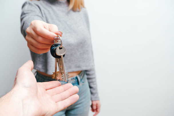 Konzentrieren Sie sich auf weibliche Hand, die Hausschlüssel hält. Immobilienmaklerin übergibt Strauß an neuen glücklichen Immobilienbesitzer. Haus und Schlüsselbund in den Händen. Lebensstil-Konzept der Menschen. - Foto, Bild