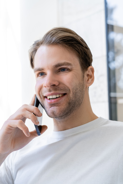 portrait of young man smiling during conversation on mobile phone - Foto, Imagen