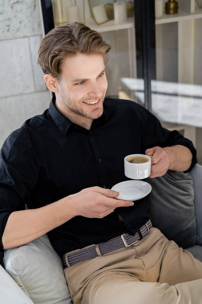happy and stylish man sitting with morning coffee at home - Фото, изображение
