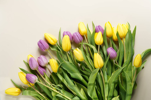 Un mazzo di tulipani gialli e viola su uno sfondo di colore beige, copia lo spazio per il testo - Foto, immagini