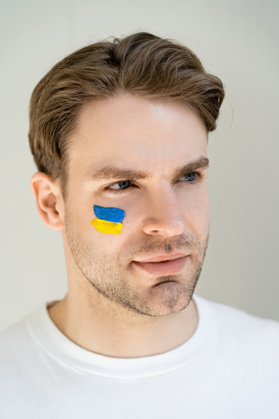 portrait of patriotic man with unkrainian flag painted on face isolated on grey - Photo, Image