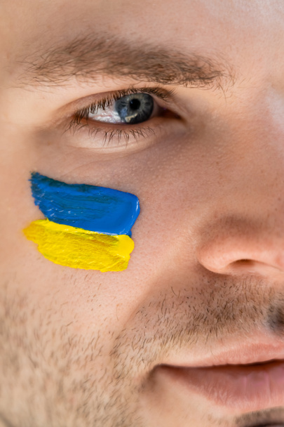 vista de cerca de la bandera ucraniana pintada en la cara del joven patriota - Foto, Imagen