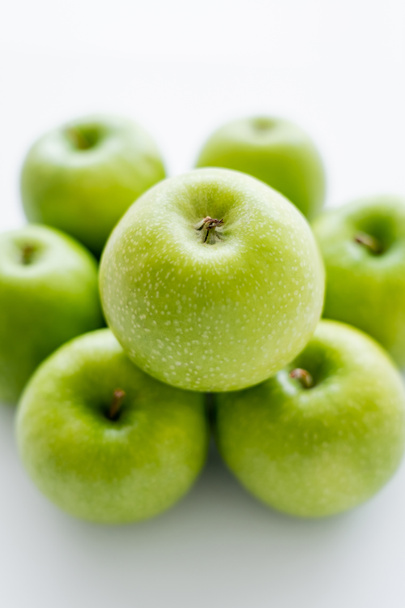 top view of green and ripe apple on blurred pile on white - Foto, afbeelding
