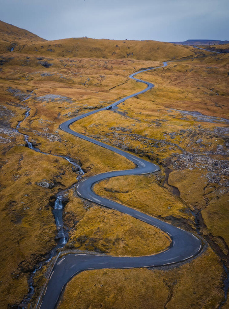 Aerial view on serpentine road on the island Streymoy near the village Nordradalur with view of Koltur island. Faroe Islands, Denmark. November 2021 - Photo, Image