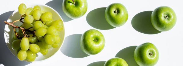 top view of apples near tasty grapes in bowl on white, banner - Foto, Imagem