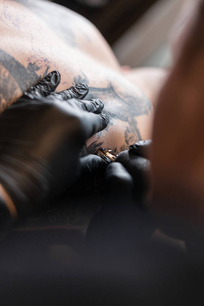 férfi profi tetováló művész fekete kesztyűvel, tetoválás, közelről - Fotó, kép