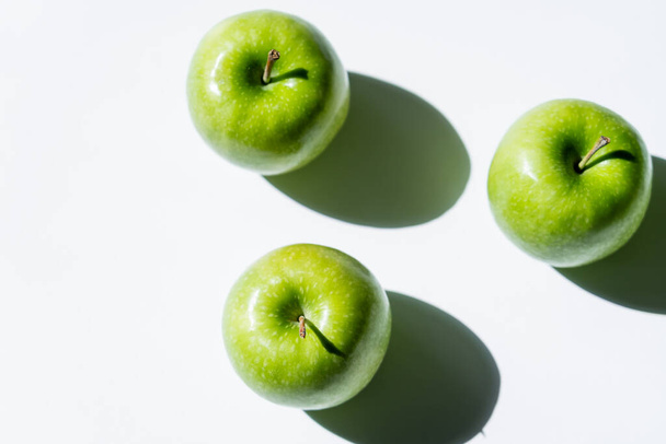 flat lay with green apples with shadows on white - Φωτογραφία, εικόνα