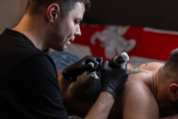 Man tattoo professional master makes a tattoo at home - Photo, Image