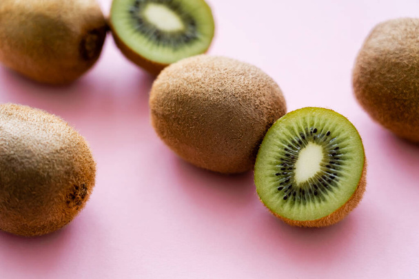 close up view of sweet whole and cut kiwi on pink  - Foto, imagen