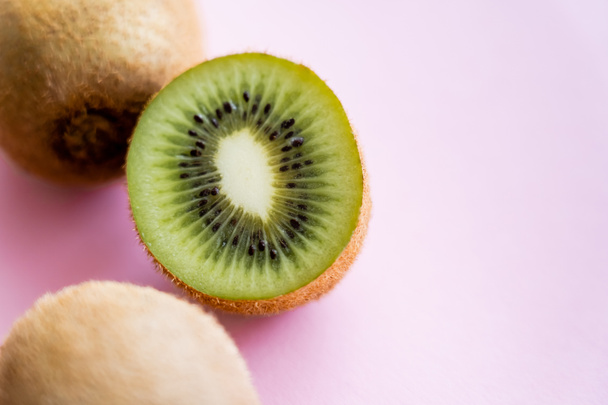 vista superior de kiwi de redução perto de frutas inteiras em rosa - Foto, Imagem