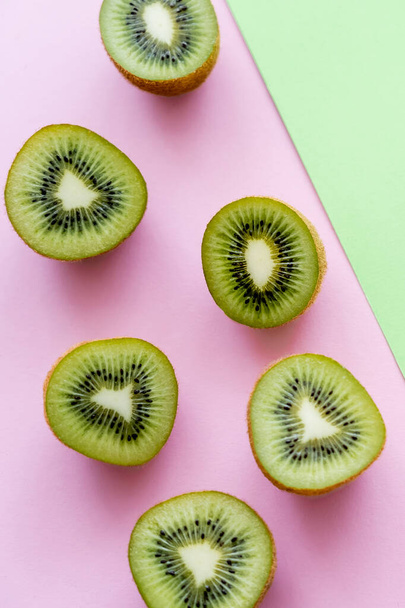 top view of halves with fresh kiwi fruit on green and pink  - Foto, Imagen