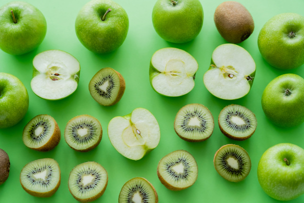 érett almák és kivi gyümölcsök lapos tojása zöld alapon  - Fotó, kép