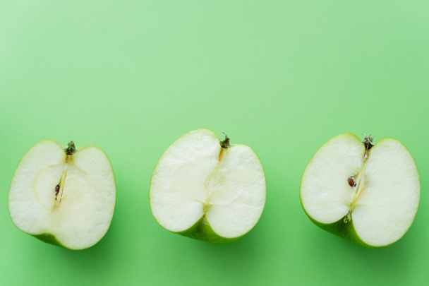 flat lay of tasty cut apples on green - Фото, изображение