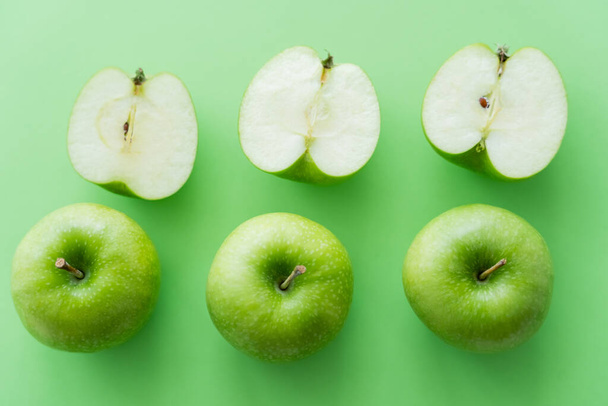 disposición plana de sabrosas manzanas enteras y cortadas en verde - Foto, imagen