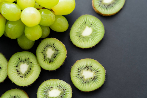 top view of green grapes and sliced kiwi on black  - Photo, Image