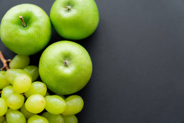 top view of tasty apples and green grapes on black - Фото, изображение