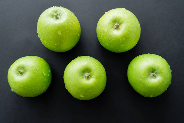 tendido plano de manzanas verdes y frescas con gotas de agua en negro  - Foto, Imagen