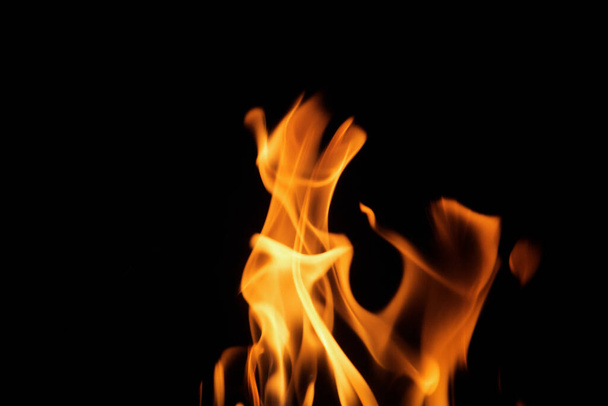 Nahaufnahme brennender Flammen auf schwarzem Hintergrund für Grafikdesign oder Tapeten. Rot und gelb, Heizenergie, die den Brennstoff in der Nacht entzündet. Abstraktes Feuer zum Kochen. - Foto, Bild