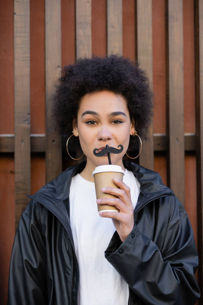 curly african american woman holding paper cup and straw with moustache - Foto, Bild