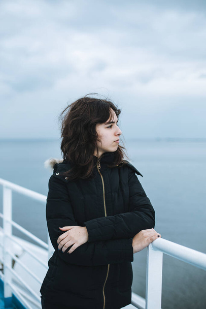 Chica joven pensativa mirando al mar desde el barco. Chica adolescente en el transbordador. Mar gris frío - Foto, imagen