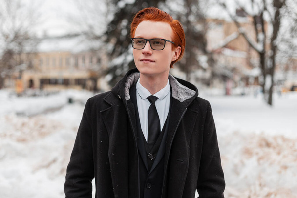 Fashion portrait of a handsome redhead  in stylish business clothes with a coat, shirt and tie walks on the street in the city. Englishman in winter outerwear - Photo, Image