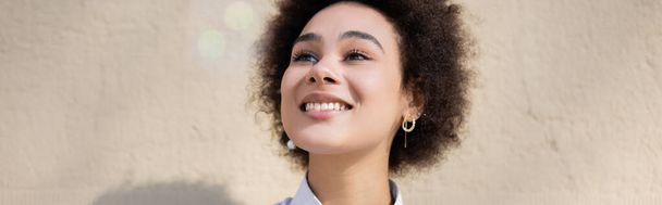 κατσαρομάλλη Αφροαμερικανή που χαμογελάει ενώ κοιτάζει αλλού, πανό - Φωτογραφία, εικόνα