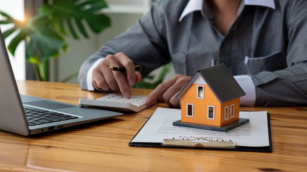 Gli uffici degli agenti immobiliari offrono contratti di vendita a domicilio ai clienti alle loro scrivanie. - Foto, immagini
