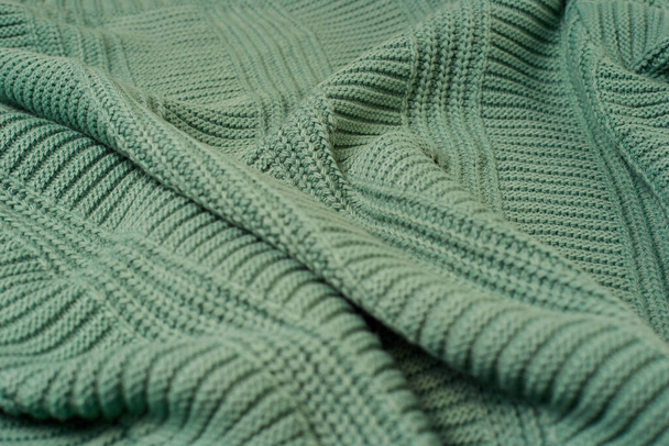 Зеленая трикотажная ткань, собранная в складки, большие вязаные свитера. - Фото, изображение
