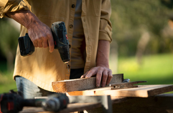 Close-up of handyman carpenter working in carpentry diy workshop outdoors with drill. - Photo, Image