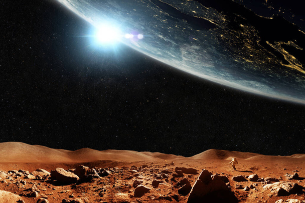 Planeta rojo Marte con estrellas y planeta Tierra, concepto de viaje espacial. Astronauta hombre del espacio camina a través del desierto rojo con montañas con vistas al espacio. - Foto, imagen