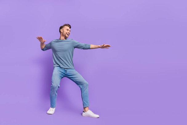 Photo of charming cool guy dressed grey shirt looking empty space dancing riding surf isolated purple color background - Zdjęcie, obraz