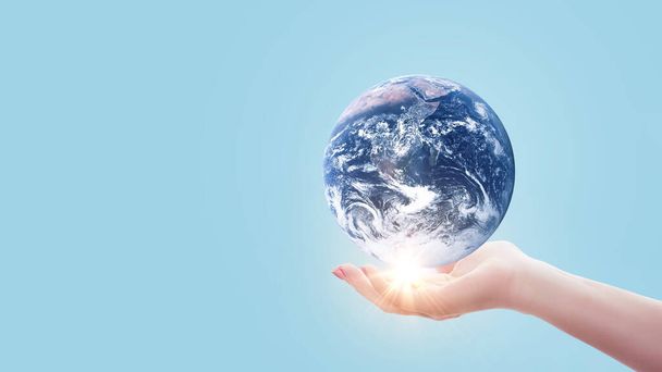 Hand holds blue planet Earth with sunset light on pastel blue color. Save Earth concept. Environment creative idea - Photo, Image