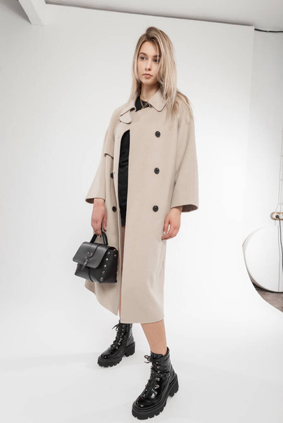 Schöne blonde Mädchen Modell in modischer Herbstkleidung mit Mantel, Schuhen und Handtasche im Studio - Foto, Bild