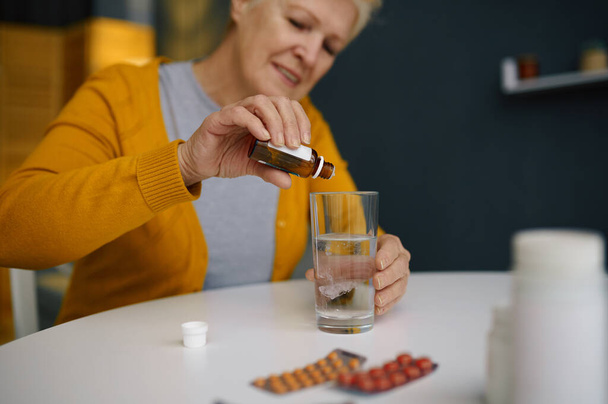 Retired elderly woman dripping medical sedative drops - Foto, Bild